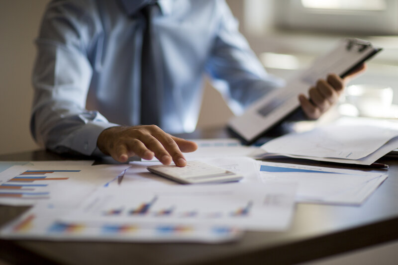 Businessman using calculator and laptop for budget planning